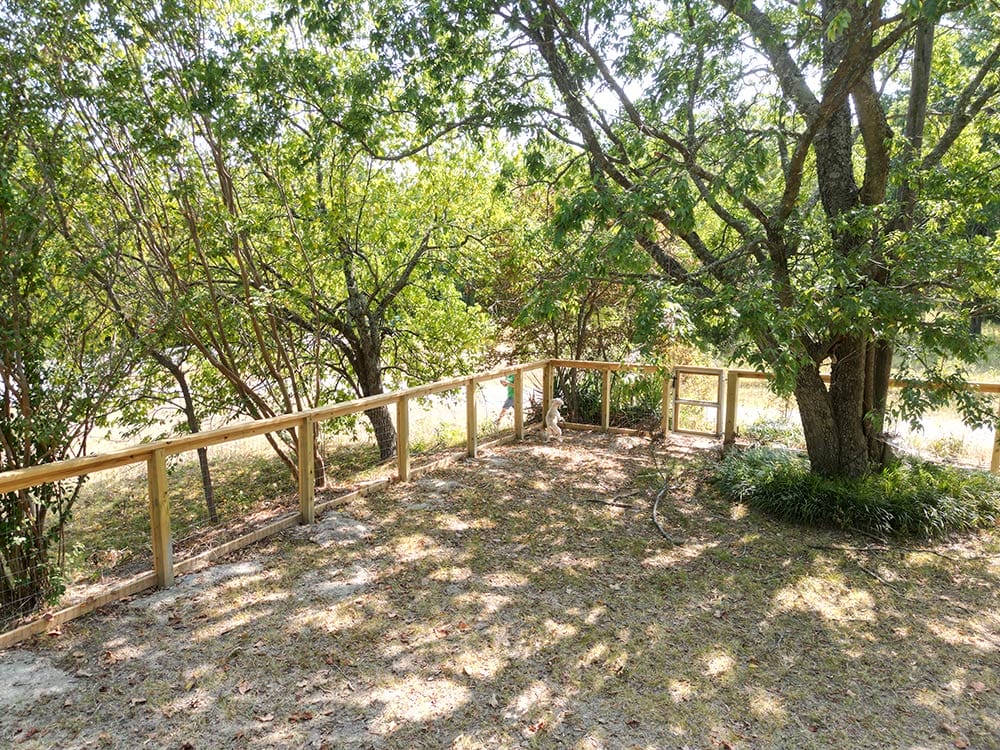 Wood rail with wire fence under trees